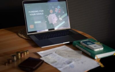 Ordinateur portable affichant une page de finance en ligne avec tirelire et documents financiers sur un bureau en bois